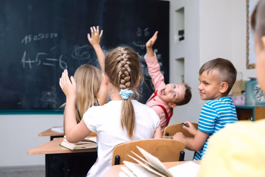 tudents raising hands in a classroom — the kind of active participation that international classroom collaboration brings to every lesson